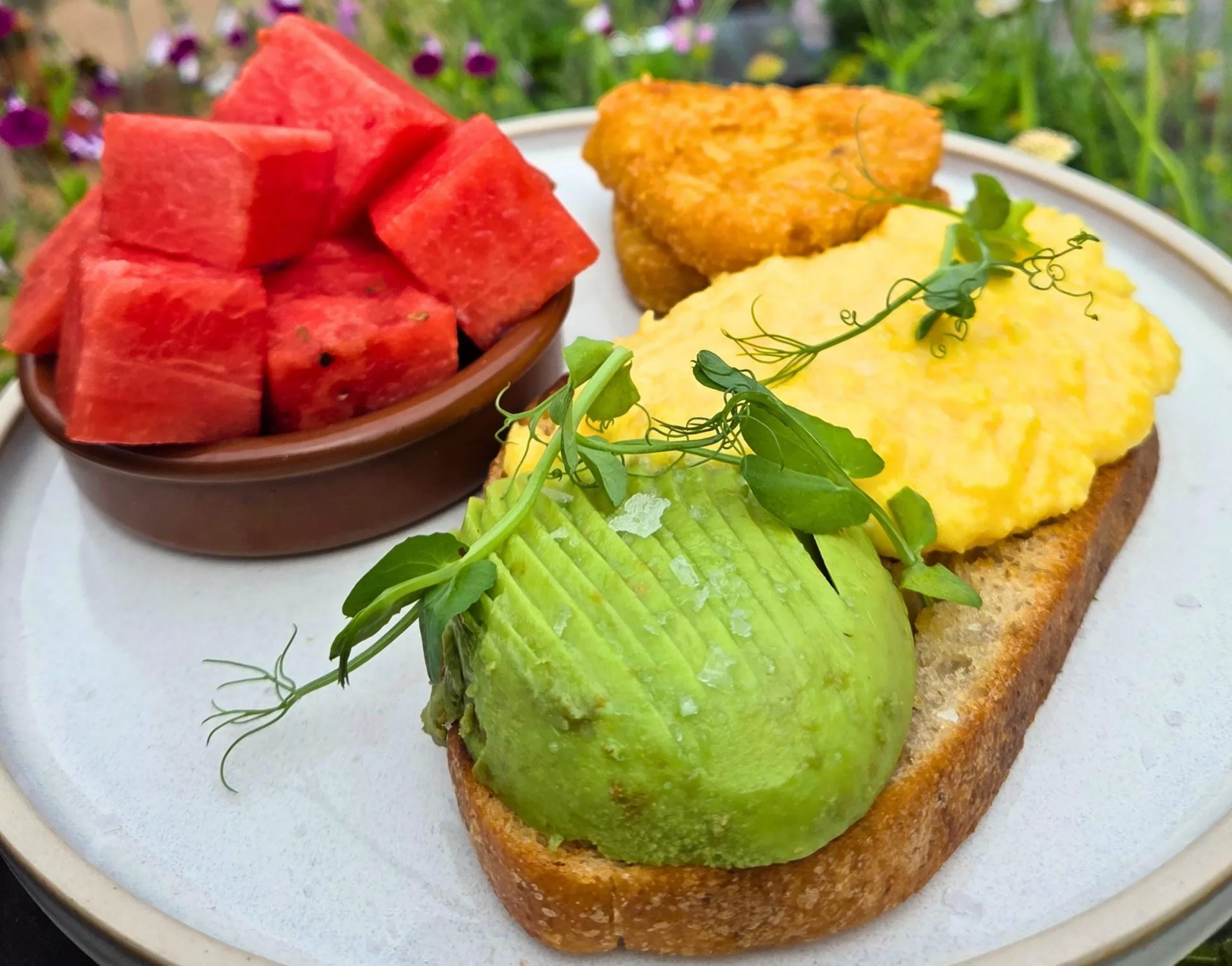 Sunshine breakfast: avocado and scrambled eggs on sourdough with hash browns and a side of melon